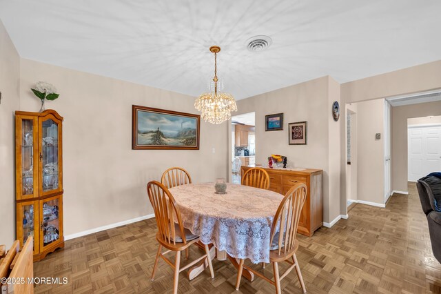 dining area with baseboards, visible vents, and a chandelier