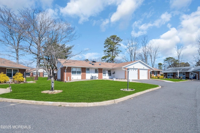 ranch-style home featuring a garage, a front yard, brick siding, and a residential view