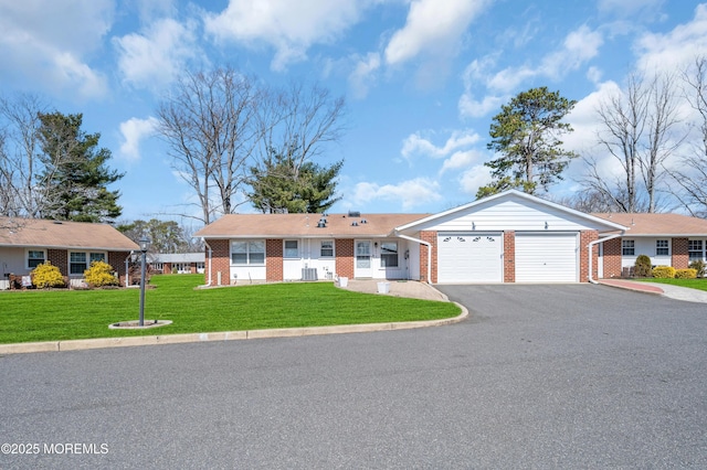 single story home with aphalt driveway, an attached garage, cooling unit, a front yard, and brick siding