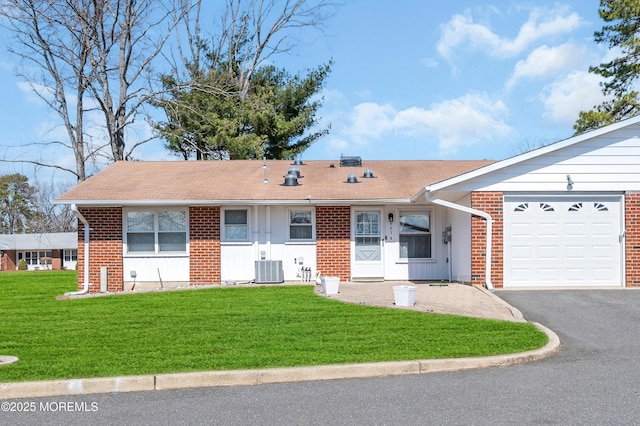 single story home featuring aphalt driveway, an attached garage, a front lawn, central AC, and brick siding