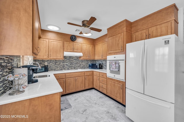 kitchen with white appliances, tasteful backsplash, under cabinet range hood, and marble finish floor