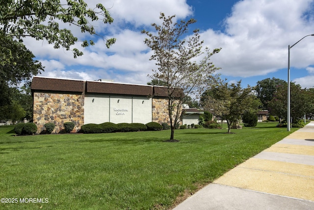 view of side of property featuring stone siding and a lawn