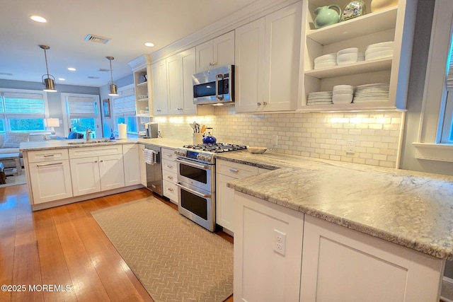 kitchen with a sink, appliances with stainless steel finishes, white cabinetry, and open shelves