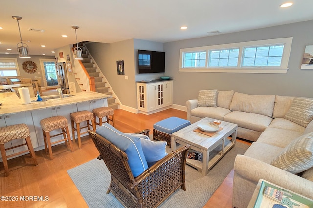 living area featuring visible vents, recessed lighting, light wood finished floors, baseboards, and stairs