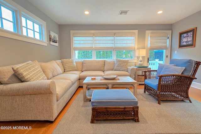 living area with recessed lighting, visible vents, and wood finished floors