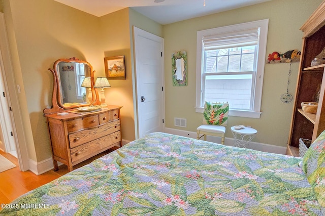 bedroom with wood finished floors, visible vents, and baseboards