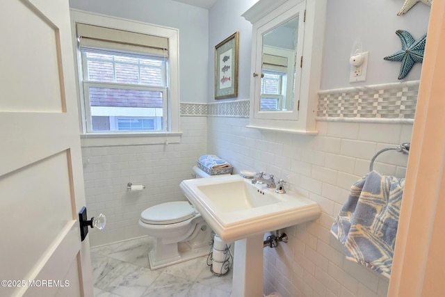 bathroom with a wainscoted wall, tile walls, toilet, and marble finish floor