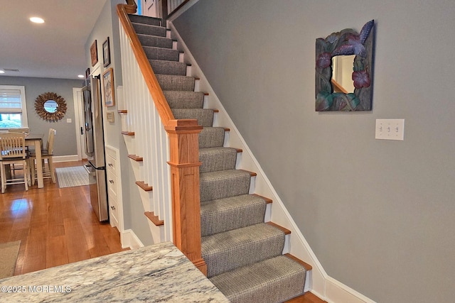 stairway with recessed lighting, baseboards, and wood finished floors