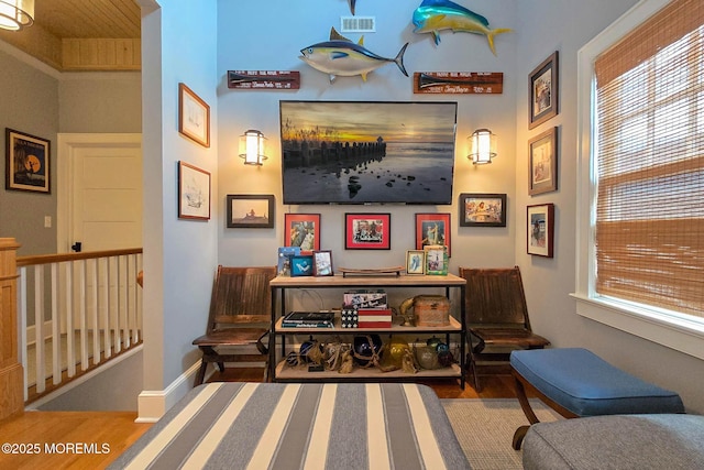 living area with plenty of natural light, wood finished floors, visible vents, and an upstairs landing