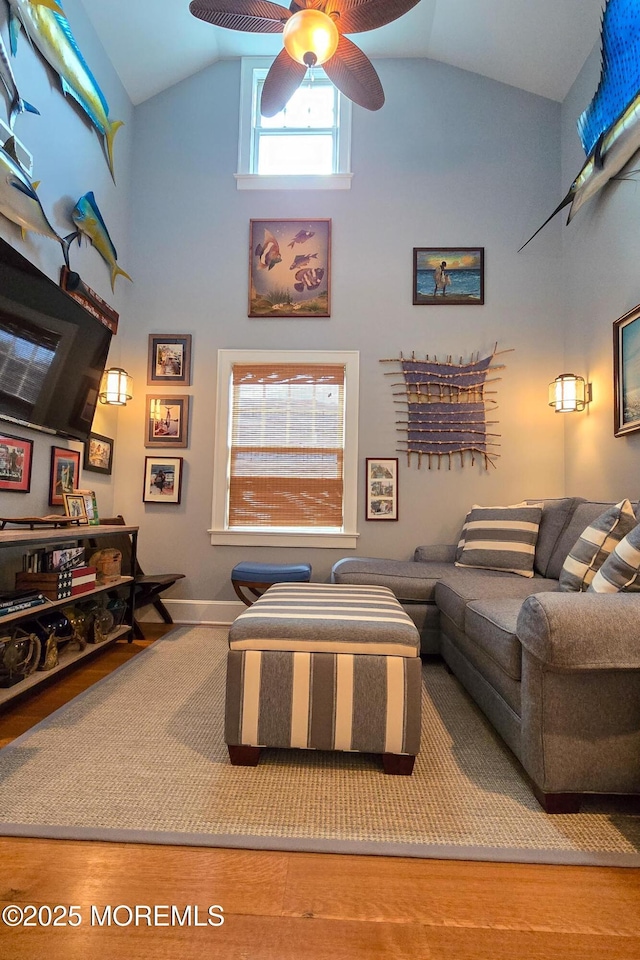 living area with baseboards, high vaulted ceiling, and wood finished floors