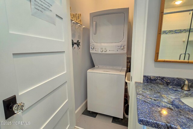 laundry area featuring laundry area, baseboards, and stacked washer and clothes dryer