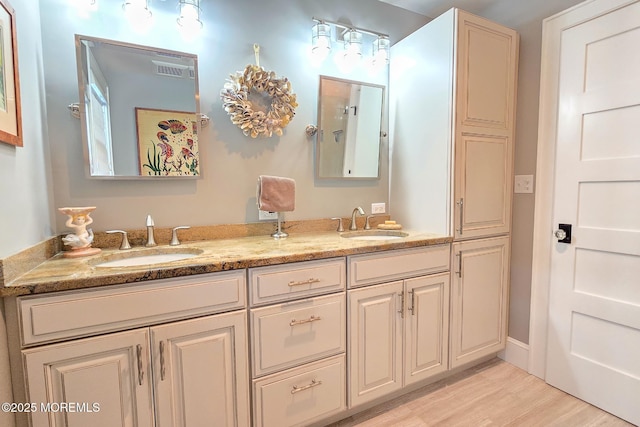 bathroom featuring double vanity, wood finished floors, visible vents, and a sink