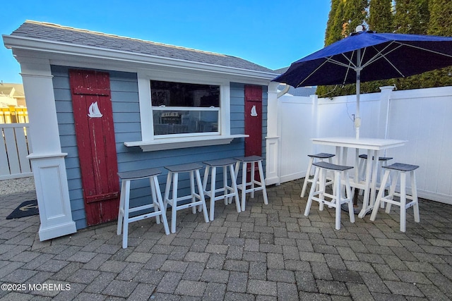 view of patio with an outbuilding, outdoor dry bar, and fence