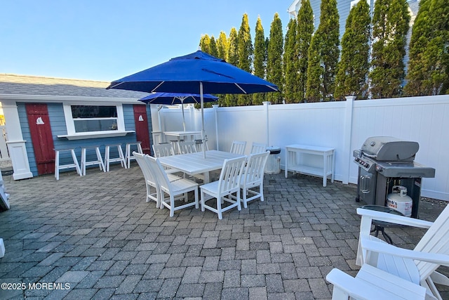 view of patio with area for grilling, outdoor dining space, and fence