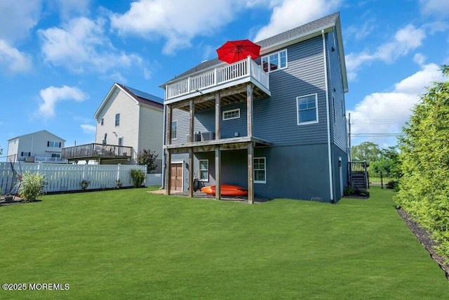 back of property with a fenced backyard, a balcony, and a yard