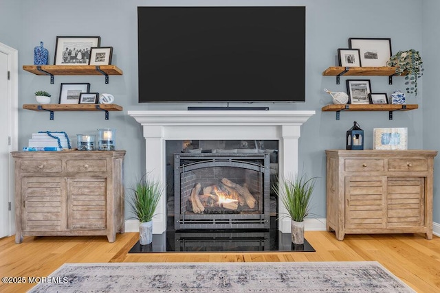 room details with wood finished floors and a lit fireplace