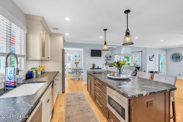 kitchen featuring appliances with stainless steel finishes, a breakfast bar area, light wood-style floors, and a sink