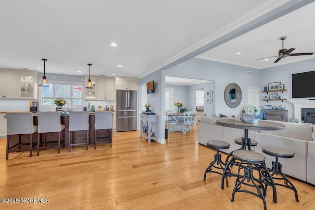 kitchen featuring light wood finished floors, open floor plan, a kitchen breakfast bar, and high quality fridge