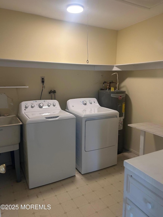 clothes washing area with a sink, water heater, washer and dryer, cabinet space, and light floors