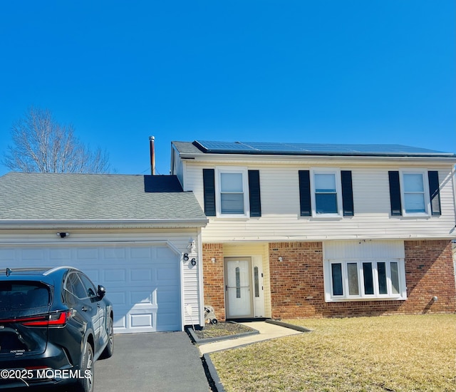 view of front of property with aphalt driveway, roof mounted solar panels, brick siding, and an attached garage