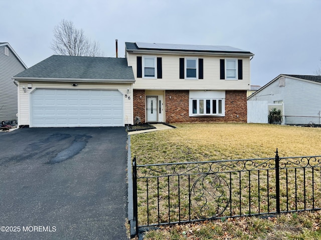 view of front facade featuring an attached garage, a front lawn, aphalt driveway, brick siding, and roof mounted solar panels