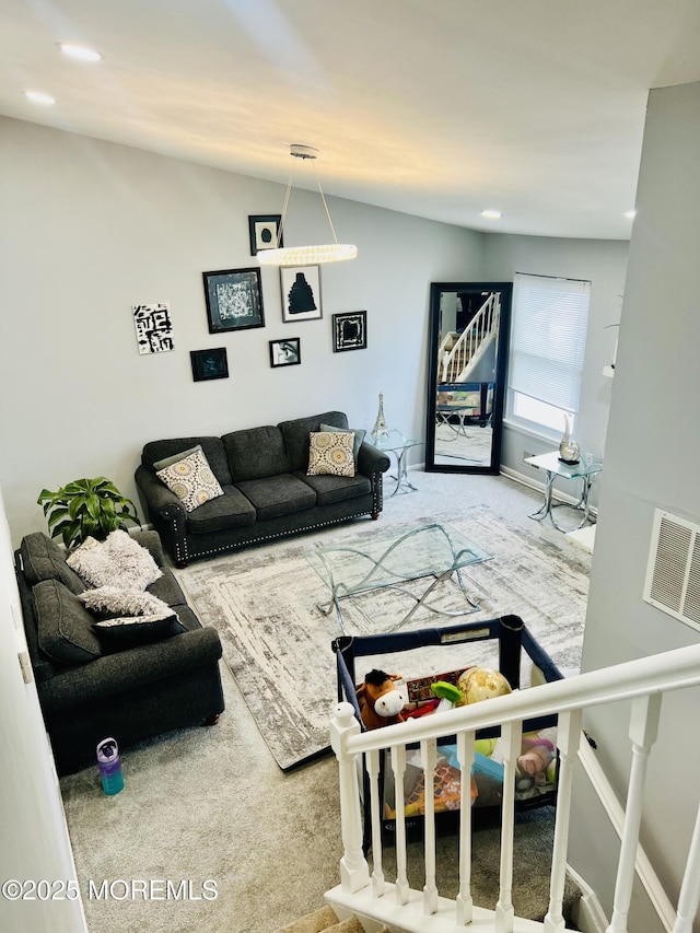 carpeted living area featuring visible vents, baseboards, and lofted ceiling