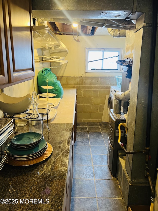 bathroom featuring stone finish flooring, washer / dryer, and concrete block wall