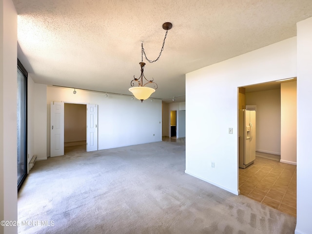 empty room featuring a textured ceiling, baseboard heating, and light colored carpet