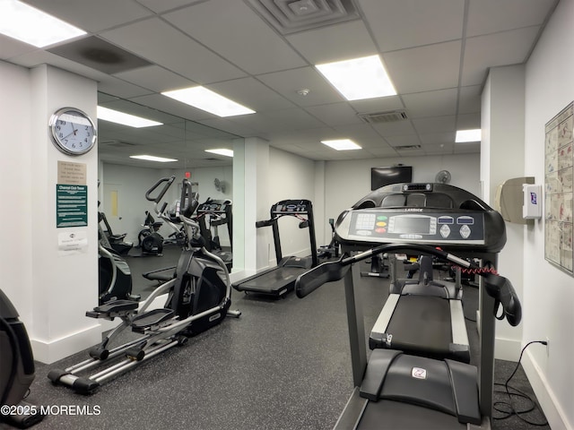 gym with a paneled ceiling, visible vents, and baseboards