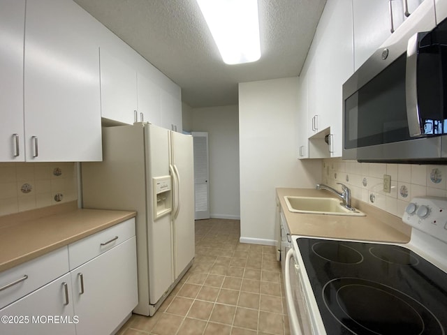 kitchen with a textured ceiling, white appliances, a sink, white cabinets, and tasteful backsplash