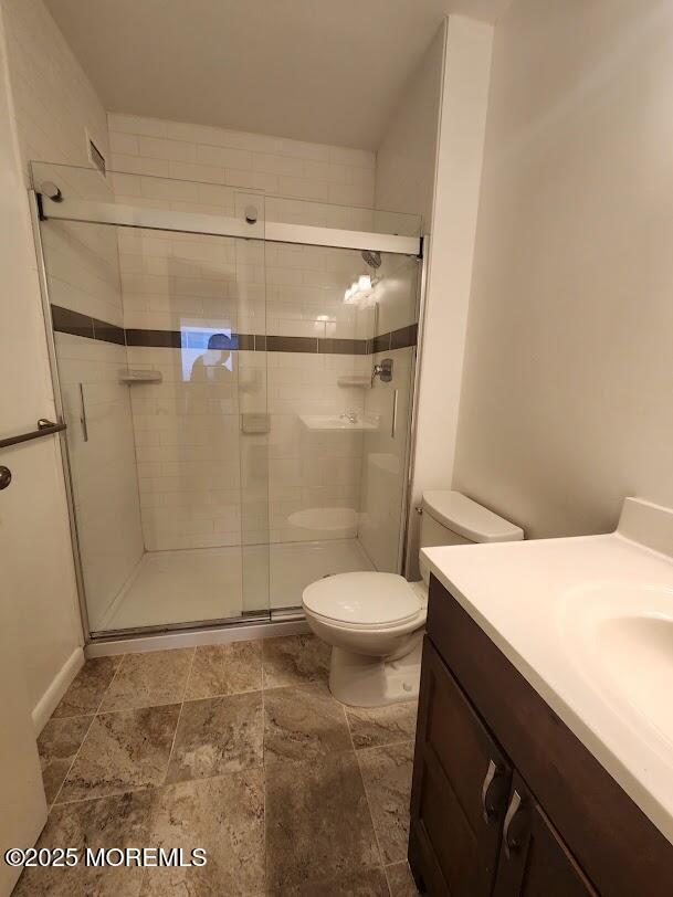 bathroom with a stall shower, vanity, and toilet