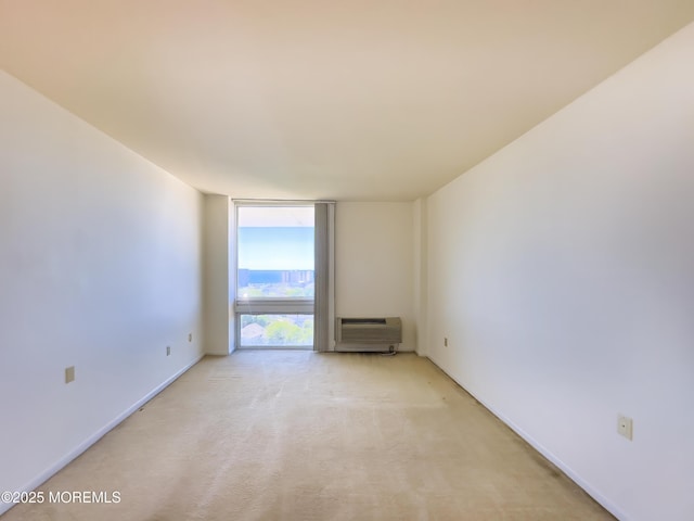 spare room featuring expansive windows, a wall mounted air conditioner, and light colored carpet