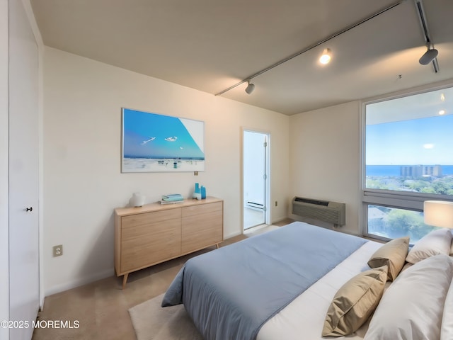 bedroom featuring a baseboard heating unit, a wall mounted air conditioner, light colored carpet, and track lighting