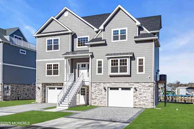 view of front of house with stairway, roof with shingles, a front lawn, stone siding, and decorative driveway