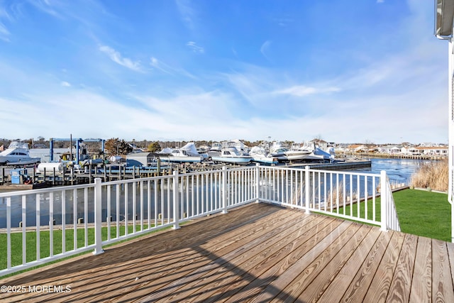 deck featuring a water view, a lawn, and a dock