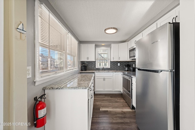 5909 Ocean Blvd, Long Beach Twp, NJ 08008 - kitchen featuring backsplash, dark wood finished floors, light stone counters, appliances with stainless steel finishes, and white cabinets