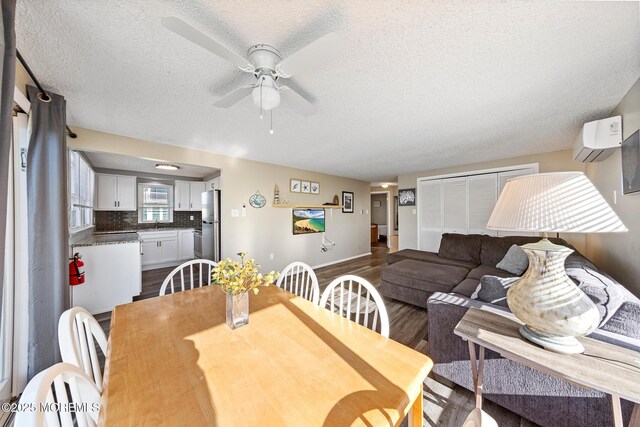 5909 Ocean Blvd, Long Beach Twp, NJ 08008 - dining room featuring a ceiling fan, baseboards, a wall mounted AC, dark wood finished floors, and a textured ceiling
