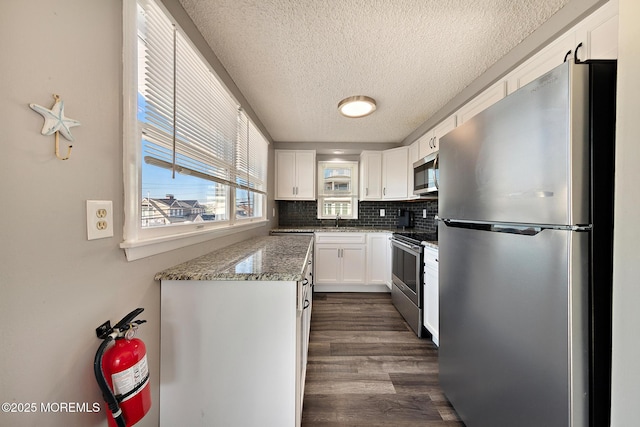 5909 Ocean Blvd, Long Beach Twp, NJ 08008 - kitchen with dark wood-style floors, a sink, decorative backsplash, appliances with stainless steel finishes, and white cabinetry