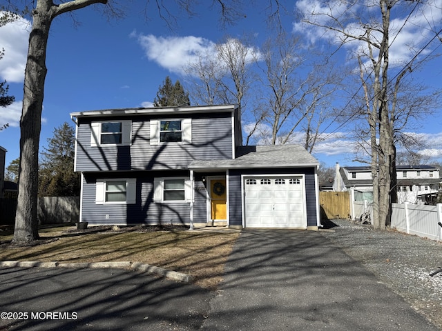 colonial-style house featuring driveway, an attached garage, and fence