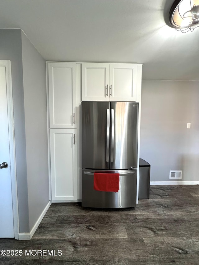 kitchen with white cabinetry, visible vents, dark wood-style flooring, and freestanding refrigerator