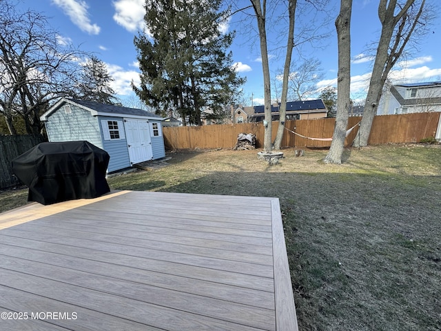 wooden deck with a fenced backyard, grilling area, an outbuilding, a storage unit, and a yard