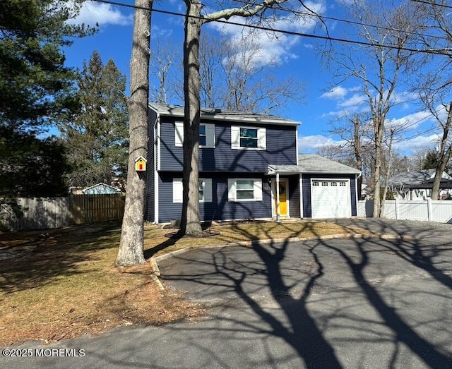 colonial home featuring fence, driveway, and an attached garage