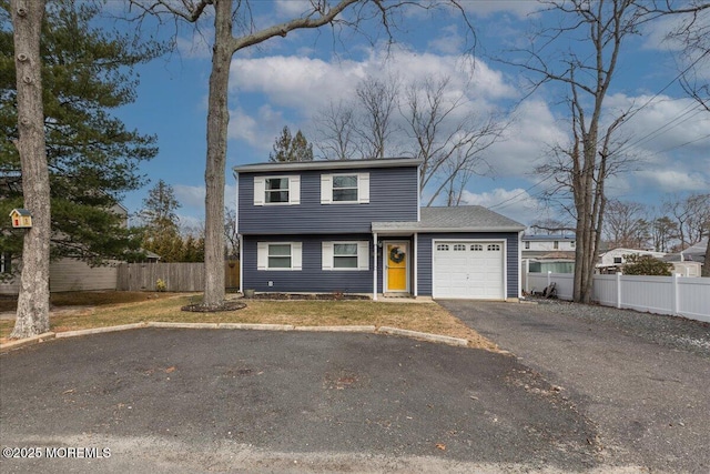 colonial home with a front yard, an attached garage, fence, and driveway