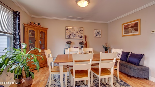 dining area featuring ornamental molding, visible vents, and light wood-style floors