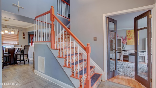 stairway with baseboards, visible vents, and crown molding