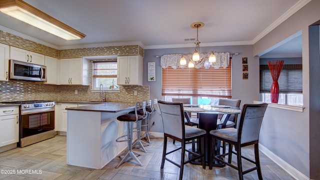 kitchen featuring white cabinets, crown molding, stainless steel appliances, and a sink