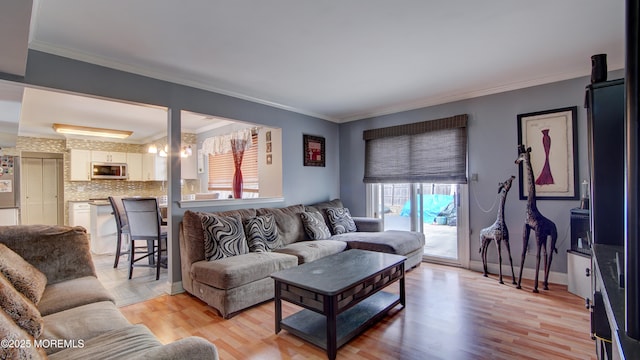 living room featuring light wood finished floors, ornamental molding, and baseboards