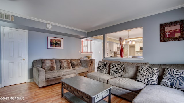 living room with a chandelier, visible vents, baseboards, light wood-style floors, and ornamental molding