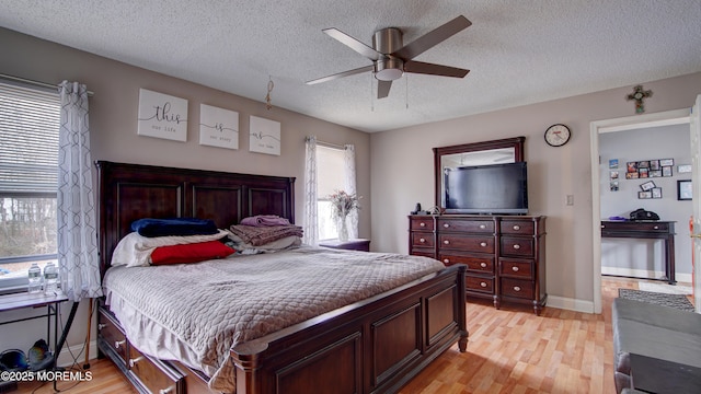 bedroom featuring a textured ceiling, ceiling fan, light wood-type flooring, and baseboards