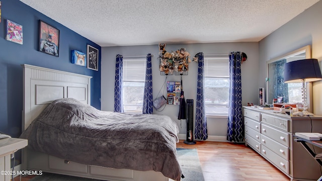 bedroom with light wood-type flooring, a textured ceiling, and baseboards